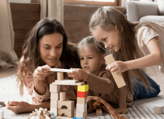 girl playing with blocks on floor with kids. How to find a babysitter. Des Moines Mom
