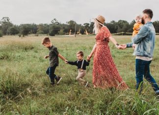family walking in field holding hands. Des Moines Mom