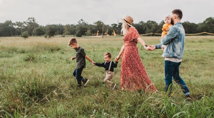 family walking in field holding hands. Des Moines Mom