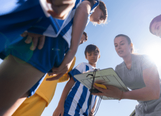 woman showing clipboard to soccer players. mom coach soccer team. Des Moines Mom